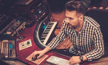 A music producer working attentively at a mixing console in a recording studio