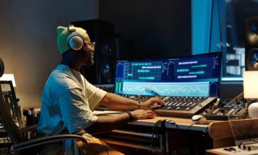 A focused audio engineer wearing high-quality headphones in a studio setting.